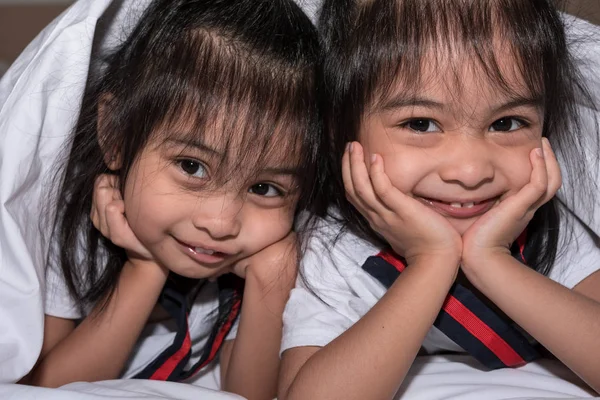 Счастливые маленькие девочки близнецы сестра в постели под одеялом с — стоковое фото