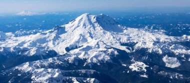 Aerial View of Idaho mountains from the sky while inside an airplane. View of brown mountains and trees covered with snow clipart