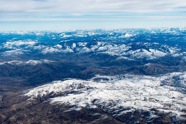 飛行機の中にいる間 アイダホ州の山々の空中ビュー 雪に覆われた茶色の山や木々の景色 — ストック写真