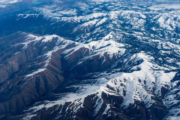 飛行機の中にいる間 アイダホ州の山々の空中ビュー 雪に覆われた茶色の山や木々の景色 — ストック写真