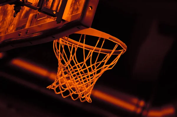 orange basket hoop and net on black background in a basketball arena. duo-tone 90\'s style.