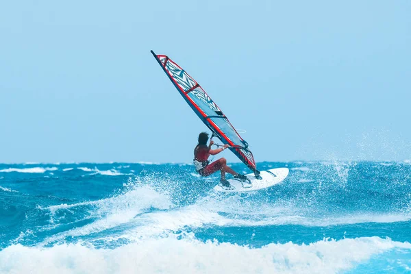 Su sporları: güneşli bir yaz öğleden sonrasında dalgalarda sörf yapan rüzgar sörfçüsü.