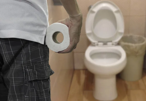 Hand houden toiletpapier roll en het invoeren van het toilet. — Stockfoto