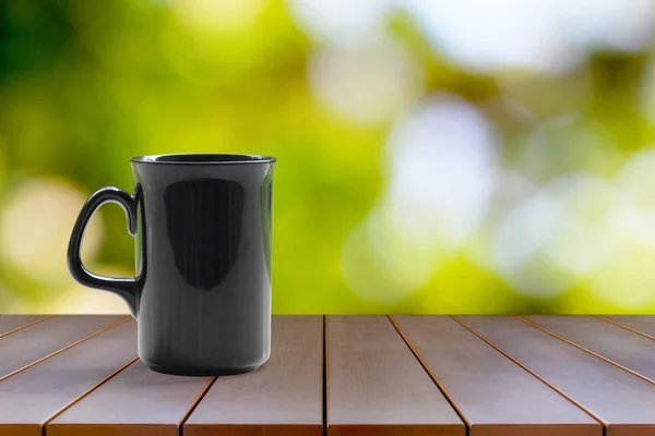 Una taza de café negro sobre una mesa de madera sobre un fondo natural — Foto de Stock