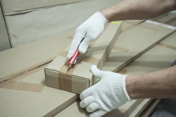 Mãos masculinas em luvas brancas com uma faca desempacotar a caixa . — Fotografia de Stock