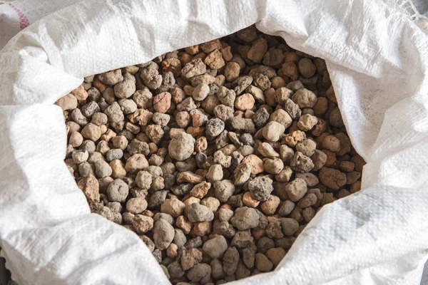 Natural mineral for construction. Expanded clay pebbles in a bag close-up. — Stock Image Natural mineral for construction. Expanded clay pebbles in a bag close-up. Royalty Free Stock Images