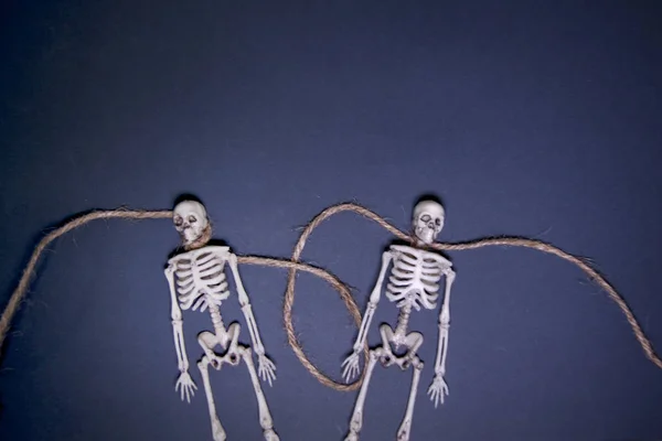 Squelettes humains sur corde sur fond sombre. Le jour de la mort. Problèmes relationnels dans la famille et l'équipe . — Photo