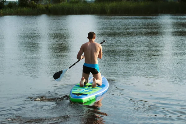 Een man drijft op een sup Board op het meer, — Stockfoto