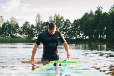 Bir erkekte bir wetsuit denizden ortaya çıkıyor.,