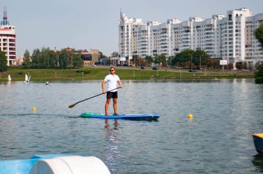 Minsk, Beyaz Rusya-Eylül 8, 2018: nehirde yüzen sörfçü ile kürek Kurulları, ayağa. spor ve insanlar, aktif yaşam tarzı, su rekreasyon kavramı,