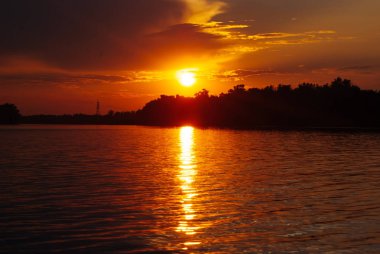 Güneş dalgalar, sıcak yaz gecesi, romantik peyzaj, parlak gün batımı nehirde yansıtılır,