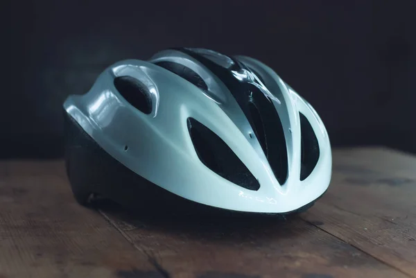 Kask rowerowy na drewniany stół, biały kask z tworzyw sztucznych na ciemnym tle, ochrona dla rowerzystów, — Zdjęcie stockowe