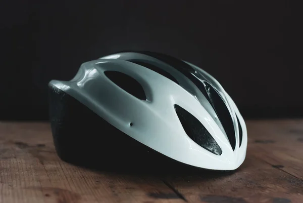 Велосипедний шолом на дерев'яному столі, білий пластиковий шолом на темному тлі, захист для велосипедиста , — стокове фото