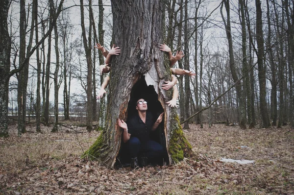 Темный и таинственный лес, испуганный человек, прячущийся под деревом, руки за деревом притягиваются к человеку, понятие человеческого страха , — стоковое фото