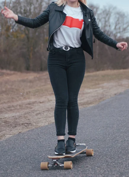 Meisje model skateboarden op een landelijke weg, moderne meisje in lederen jas op een skateboard — Stockfoto