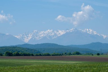 Dağ manzarası, Kafkasya'nın dağ zirvelerinin arka planında yeşil çayır,