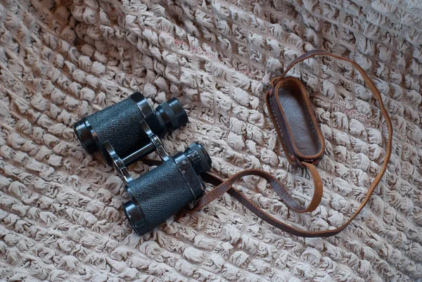 Vintage binoculars on textured blanket, old Soviet binoculars,