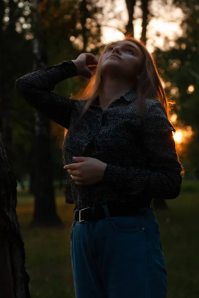 Uma jovem garota do campo, aproveitando o tempo no parque com o pôr do sol no fundo — Fotografia de Stock