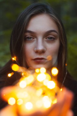 Elinde sarı bir çelenk tutan genç bir kız, bir çelenk yakın çekim bir portre,