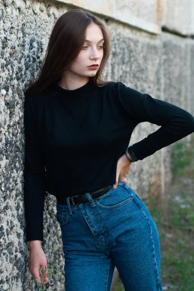 Mooie slanke meisje in blauwe jeans poseren op de betonnen muur — Stockfoto