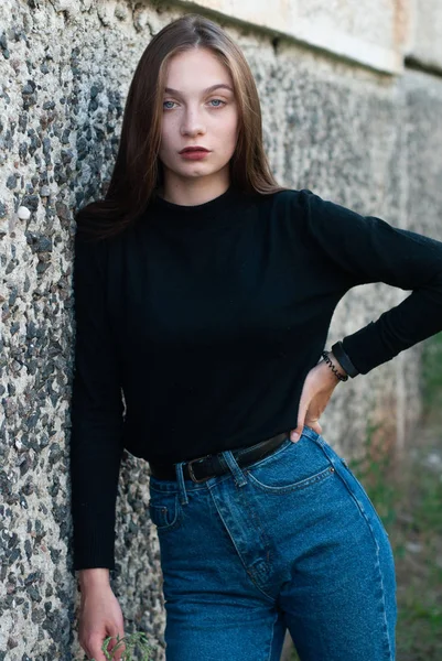 Menina fina bonita em jeans azul posando na parede de concreto — Fotografia de Stock