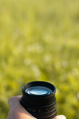 Yeşil çim arka planda fotoğrafçı elinde kamera lens, kamera markası için reklam şablonu,