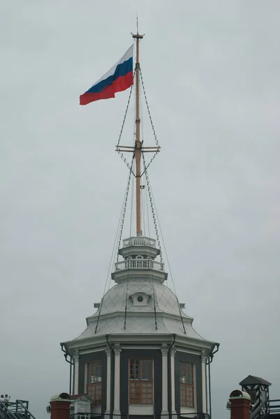De vlag van Rusland is een nationaal symbool in de wind. De Russische vlag wappert in de wind tegen een witte bewolkte lucht. Russische vlag op de vlaggenmast — Stockfoto