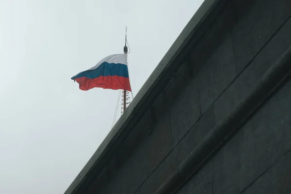 The flag of Russia is a national symbol in the wind. The Russian flag flutters in the wind against a white cloudy sky. Russian flag on the flagpole