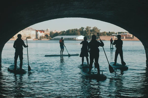 橋の下に浮かぶ水上のパドルグループに立ち、パドルボード上のサンクトペテルブルクの創造的なツアー, — ストック写真