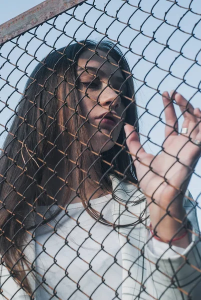 Portrait of a girl in a white T-shirt near a metal grid, — Stock Photo, Image