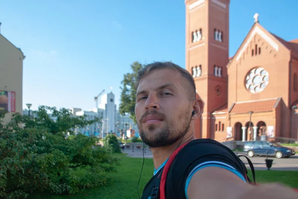 Een toerist neemt een selfie op de achtergrond van een rode kerk in Minsk, Wit-Rusland, — Stockfoto