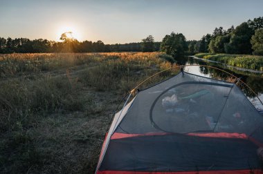 Gün batımında çadır, nehir kenarında cibinlik.,