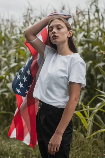 Девушка с флагом США на фоне высоких кукурузных кустов, концепция Дня труда, — стоковое фото