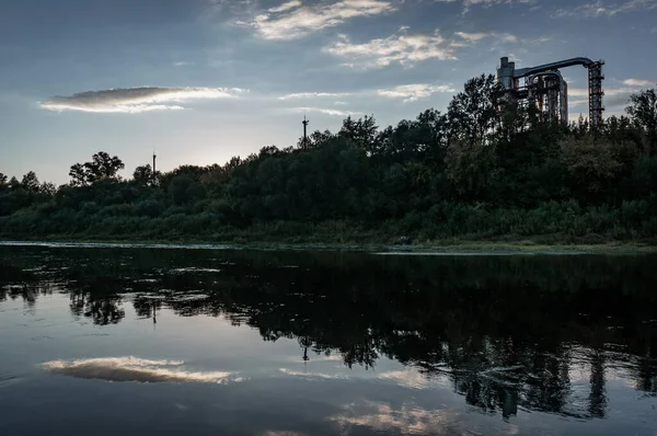 Fábrica en la orilla del río, tuberías de fábrica se reflejan en el agua, — Foto de Stock