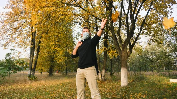 Egy férfi orvosi maszkban örül az ősz érkezésének., — Stock Fotó