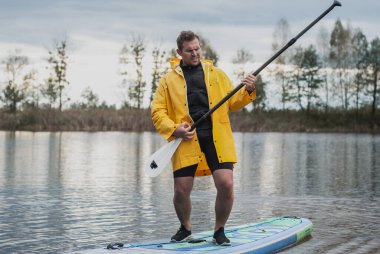 Şişme tahtada kürekle eğlenen bir adam.,
