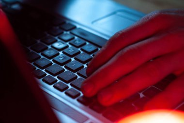 Dizüstü bilgisayarda çalışan bir adam yakın plan, elleri klavyede.,