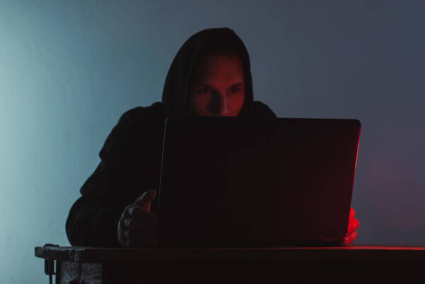 the hooded man is working on a laptop,