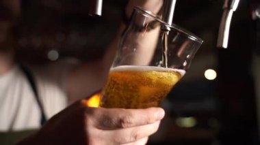 Barmen bardağa köpüklü bira dolduruyor.