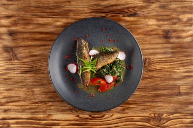 Sebze garnitür ile kızarmış Uskumru balığı: Hindistan cevizi sütü, turp, soğan ve pişmiş domates bir moderm siyah plaka üzerinde servis ıspanak