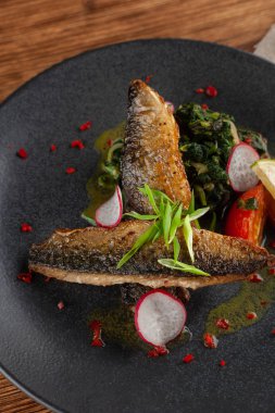 Sebze garnitür ile kızarmış uskumru balık yakın: Hindistan cevizi sütü, turp, soğan ve pişmiş domates bir moderm siyah plaka üzerinde servis ıspanak