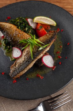 Sebze garnitür ile kavrulmuş uskumru balık ağız sulandıran: Hindistan cevizi sütü, turp, soğan ve pişmiş domates bir moderm siyah plaka üzerinde servis ıspanak