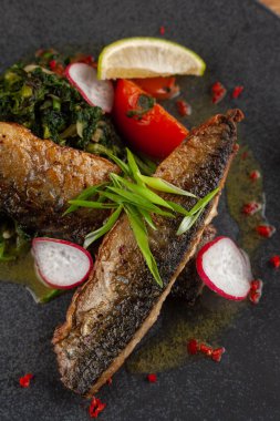 Sebze garnitür ile kavrulmuş uskumru balık ağız sulandıran: Hindistan cevizi sütü, turp, soğan ve pişmiş domates bir moderm siyah plaka üzerinde servis ıspanak