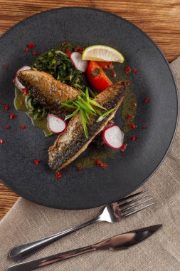 Sebze garnitür ile kavrulmuş uskumru balık ağız sulandıran: Hindistan cevizi sütü, turp, soğan ve pişmiş domates bir moderm siyah plaka üzerinde servis ıspanak