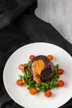 Yeşil fasulye ve taze kiraz domates ile kavrulmuş Orta nadir Mignon fileto, bir restoranda sağlıklı bir akşam yemeği için krem sos ile süslenmiş