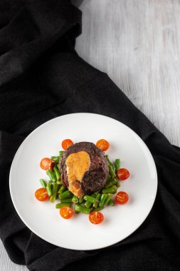 Yeşil fasulye ve taze kiraz domates ile kavrulmuş Orta nadir Mignon fileto, bir restoranda sağlıklı bir akşam yemeği için krem sos ile süslenmiş