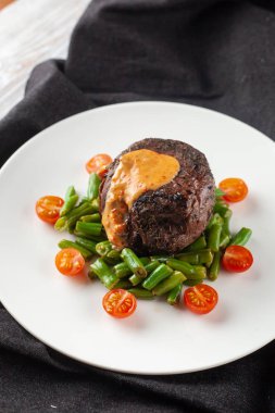 Yeşil fasulye ve taze kiraz domates ile kavrulmuş Orta nadir Mignon fileto, bir restoranda sağlıklı bir akşam yemeği için krem sos ile süslenmiş