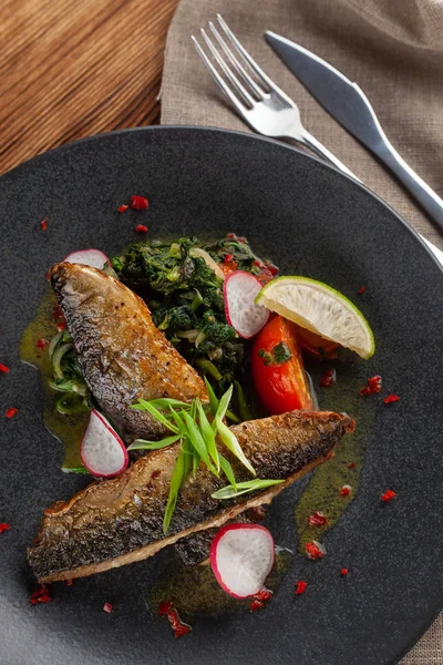 Sebze garnitür ile kızarmış Uskumru balığı: Hindistan cevizi sütü, turp, soğan ve pişmiş domates bir moderm siyah plaka üzerinde servis ıspanak