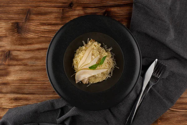 Bir restoranda gurme akşam yemeği için rendelenmiş parmesan, fesleğen ve dilimlenmiş olgun armut ile İtalyan kremsi risotto