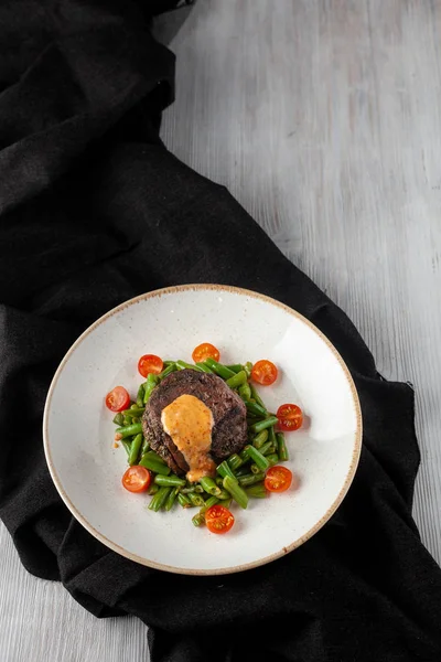 Średnio rzadkie filet z Mignon pieczone z zielonej fasoli i świeżych pomidorów wiśniowych, ozdobione kremowym sosie na zdrowy obiad w restauracji — Zdjęcie stockowe